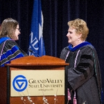 Christine Rener and faculty member smile while shaking hands